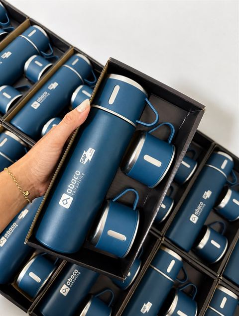 Kits de garrafa térmica azul com canecas, gravados com o logo do cliente e prontos na embalagem.
